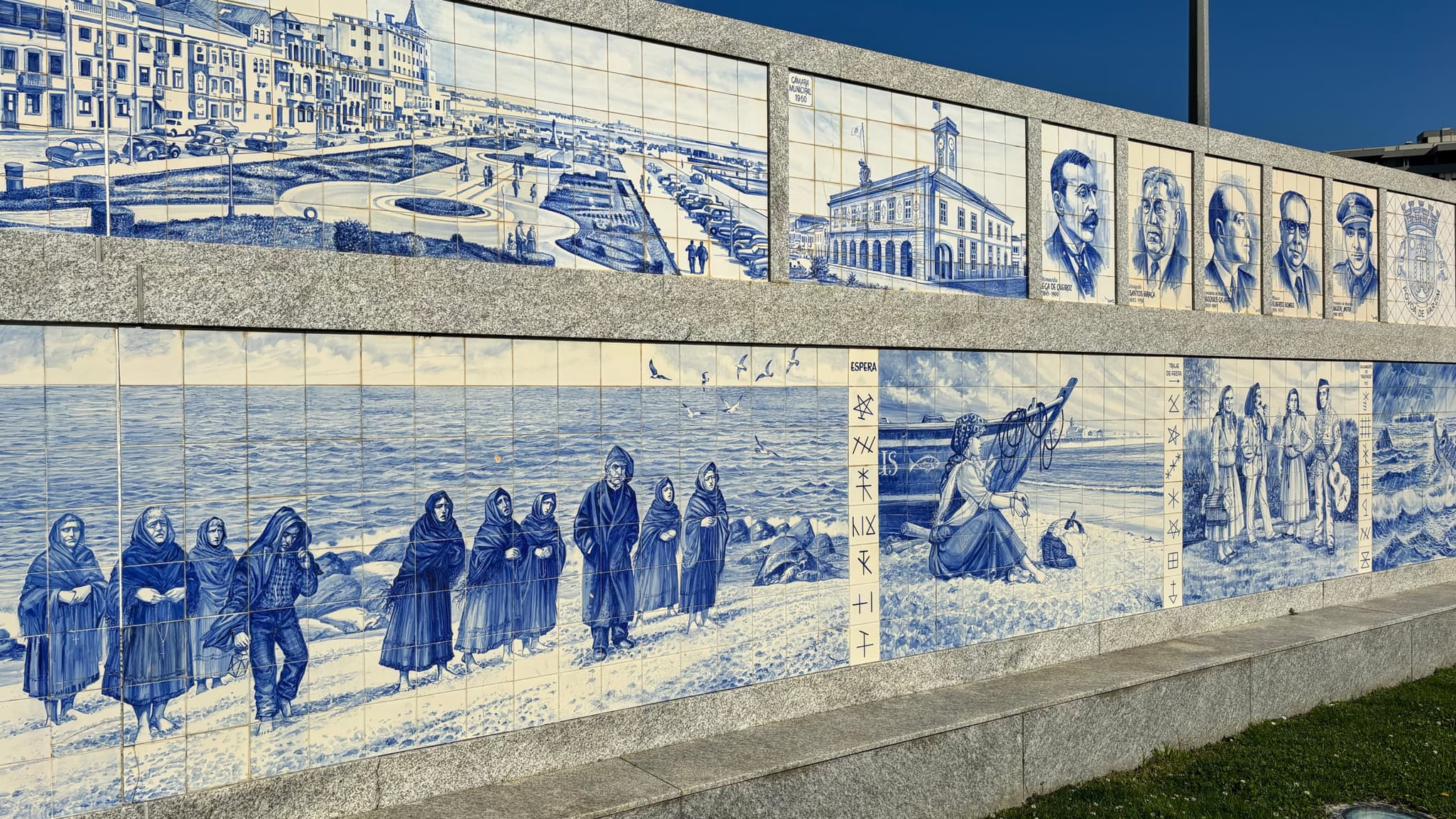 A mural composed of blue and white tiles depicting various scenes and portraits, including people in traditional clothing, a boat on the shore, and architectural elements