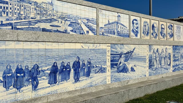 A mural composed of blue and white tiles depicting various scenes and portraits, including people in traditional clothing, a boat on the shore, and architectural elements