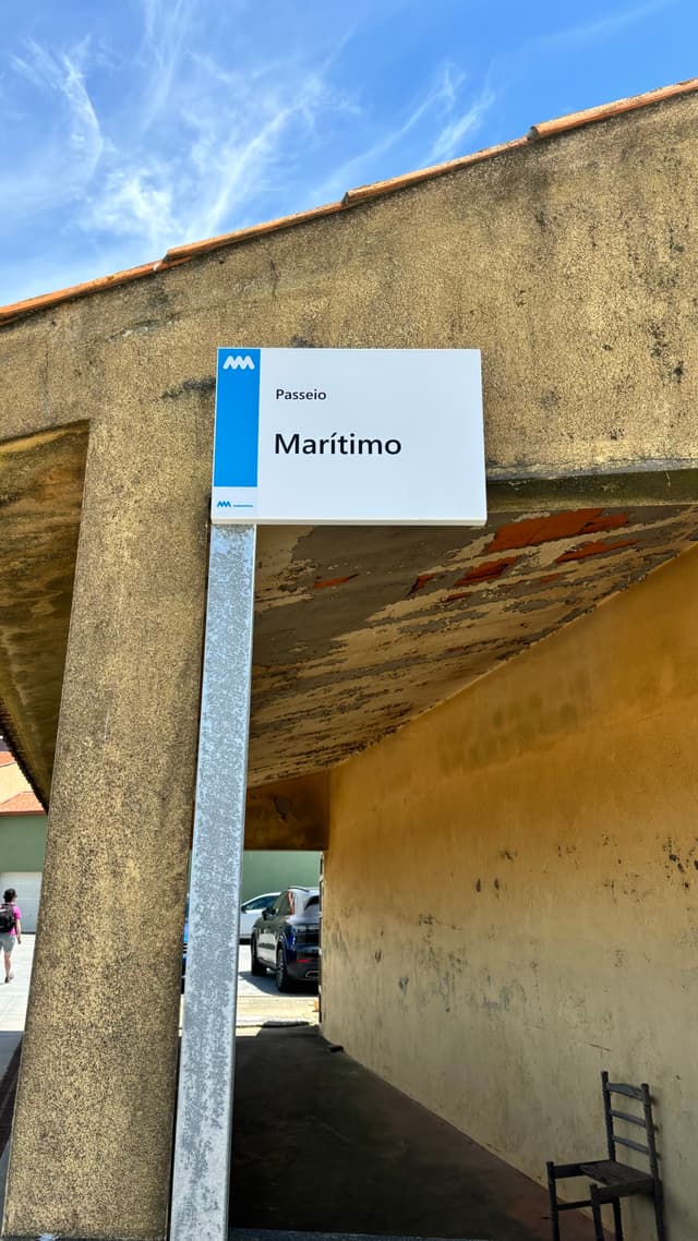A sign labeled Maritimo is mounted on a pole next to a weathered concrete structure under a blue sky